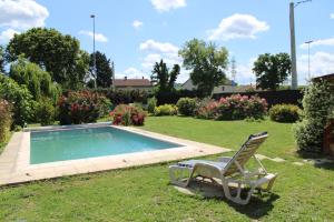 a chair sitting in the grass next to a swimming pool at Aux jardins d'Héloise in Crest