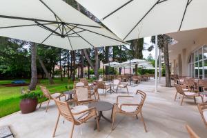 an outdoor patio with tables and chairs and umbrellas at Hotel Emaus in Novigrad Istria