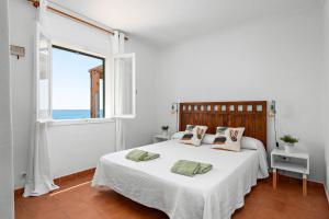 a white bedroom with a bed and a window at Mon Palau in Sant Lluis