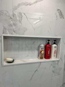 a bathroom shelf with two bottles of soap and a shower at BRAND NEW lower home with EXCLUSIVE Bathroom in Toronto