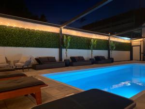 una piscina en un patio trasero por la noche con luces en XXL rooms&spa, en Osijek