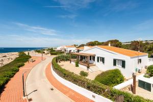 a white house with a pathway next to the ocean at Mon Palau in Sant Lluis