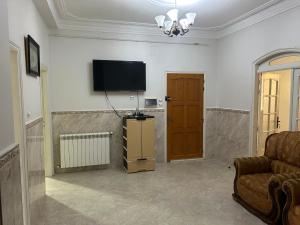 salon z kanapą i telewizorem na ścianie w obiekcie Yassine's home w mieście Dżidżili