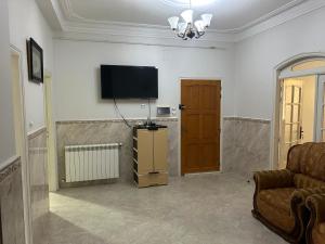 a living room with a couch and a television on a wall at Yassine's home in Jijel