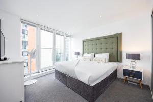a bedroom with a large bed and a large window at Austin David Apartments ExCeL in London