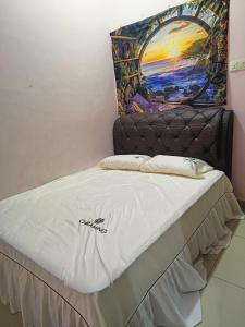 a bed in a room with a painting on the wall at perdana homestay in Ipoh
