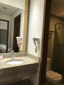 ein Badezimmer mit Waschbecken, Toilette und Spiegel in der Unterkunft Olímpia Park Resort in Olímpia
