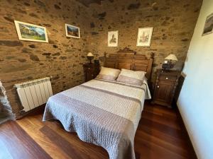 Eira de Bergondo في Bergondo: غرفة نوم بسرير في غرفة بجدران حجرية