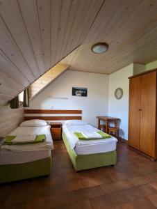 a bedroom with two beds and a wooden ceiling at Apartamenty SnowHouse in Duszniki Zdrój