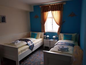 two beds in a room with blue walls and a window at Hotel & Café Schachtenburg in Schlitz
