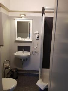 a bathroom with a sink and a toilet and a mirror at Hotel & Café Schachtenburg in Schlitz