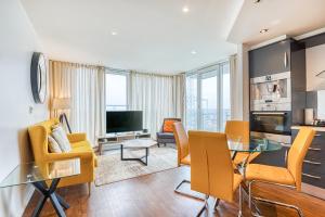 a living room with a table and chairs and a television at Austin David Apartments ExCeL in London