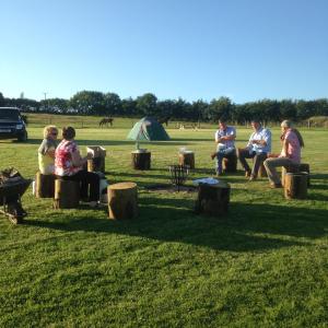 a group of people sitting in a field with a tent at Headgate Farm Camp Site - Pitches Only - Bring your own tent or van in South Molton +4 photos