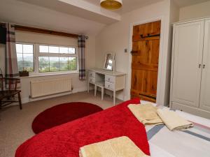 1 dormitorio con 1 cama con alfombra roja y ventana en Aberdauddwr en Llanwnen