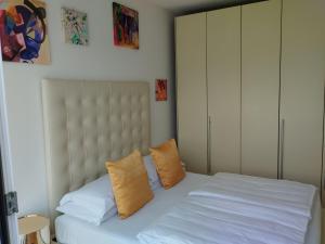 ein Schlafzimmer mit einem weißen Bett und orangefarbenen Kissen in der Unterkunft Villa Gabizza villa singola con jacuzzi privata in Malcesine