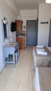 a room with two beds and a desk and a kitchen at Galini Beach in Plakias