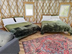 a room with two beds and a couch and a rug at YOURTE du FJORD in Sacré-Coeur-Saguenay