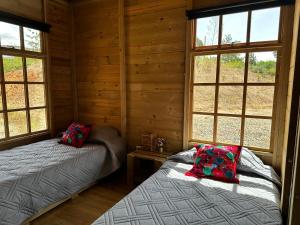 two beds in a log cabin with windows at KUYAY in Ráquira