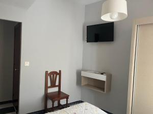 Zimmer mit einem Stuhl und einem TV an der Wand in der Unterkunft Hotel Plaza Damasco in Almuñécar