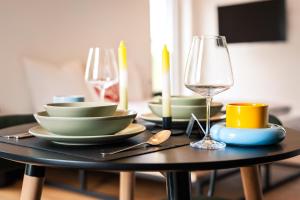 a table with plates and a glass of wine at Einzimmer Wohlfühlapartment DREI klimatisiert in Friedrichshafen
