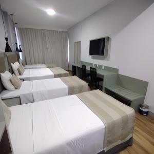 a hotel room with three beds and a television at Residencial Sausalito in Rio de Janeiro