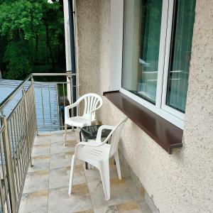 two white chairs sitting on a balcony with a window at Pokoje Klonowa in Kołobrzeg +53 photos
