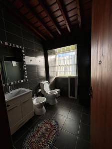uma casa de banho com 2 WC, um lavatório e um espelho. em Casa da Madrinha Graciosa em Trás dos Pomares