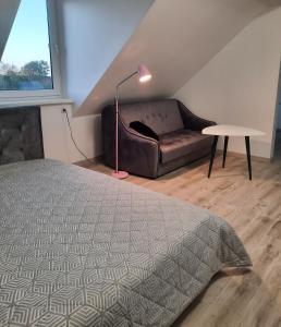 a bedroom with a bed and a couch and a lamp at Birds&Fish Ventė in Ventė