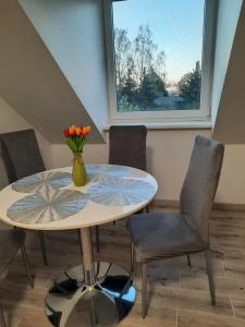 a table and chairs with a vase of flowers on it at Birds&Fish Ventė in Ventė