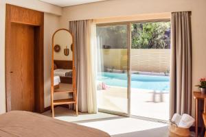 a bedroom with a view of a swimming pool at Mandraki Village Boutique Hotel in Koukounaries