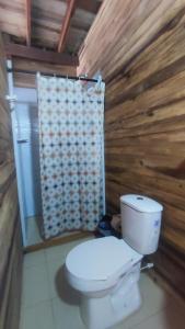 a bathroom with a toilet and a wooden wall at Zakua Beach in Guachaca