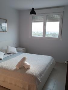 a white bedroom with a bed with a towel on it at Beach,s House in Playa del Puig in La Torre