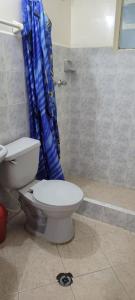 a bathroom with a toilet and a blue shower curtain at Hotel Colonial El Bosque in Tunja