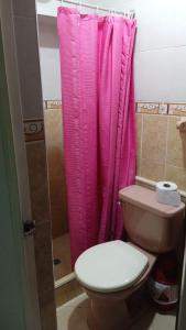 a bathroom with a pink shower curtain and a toilet at Hotel Colonial El Bosque in Tunja