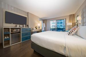 a large bedroom with a large bed and a flat screen tv at Hotel BLU in Vancouver
