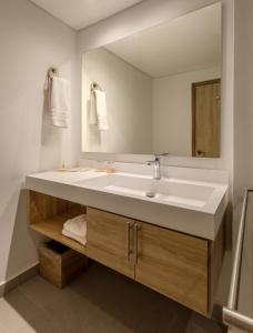 uma casa de banho com um lavatório branco e um espelho. em GHL Hotel Club el Puente em Girardot