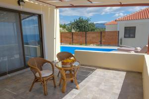 a patio with two chairs and a table with a bowl of fruit at Dream Beyond Luxury Apartments in Órmos Koumaíïkon