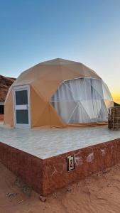 wadi rum fox road camp & jeep tour في وادي رم: خيمة جلوس فوق مبنى في الصحراء