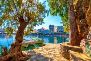 a boat on a river with trees and buildings at My Aunts House in Agios Nikolaos
