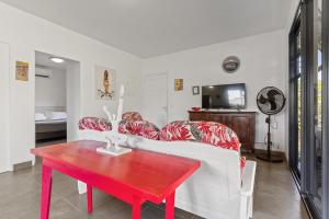 a living room with a red table and a white couch at Magie de Moorea Serenite in Temae