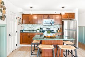 檀香山Stylish Stay at Waikiki, Close to Beach, Parking的厨房配有木制橱柜和带凳子的台面