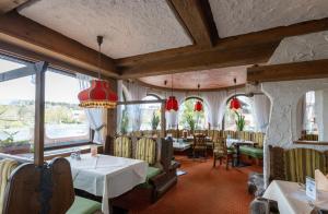 un comedor con mesas, sillas y ventanas en Hotels am Kranichsee, en Hahnenklee-Bockswiese