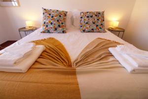 a bed with two towels on it with two lamps at Casa do Altinho in Vila Nova de Milfontes