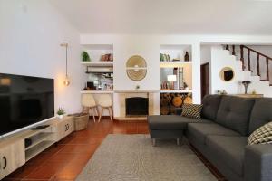 a living room with a couch and a television at Casa do Altinho in Vila Nova de Milfontes