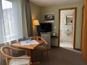 a hotel room with a table and a bathroom at Villa Dorothea in Heringsdorf