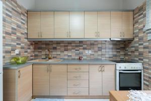 a kitchen with wooden cabinets and a sink at Romeo apartment in Lixouri +22 photos
