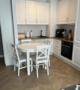 biała kuchnia z białym stołem i krzesłami w obiekcie Tani Nocleg Ełk - Apartament I love Ełk w mieście Ełk