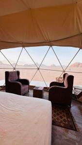 a tent with two chairs and a view of the desert at wadi rum fox road camp & jeep tour in Wadi Rum