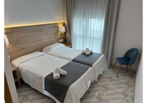 una habitación de hotel con 2 camas y una silla en Hostal Santa Clara, en L'Estartit