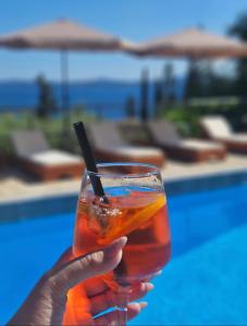 a person holding a drink in front of a pool at Hotel Barbati Sea View B&B in Barbati